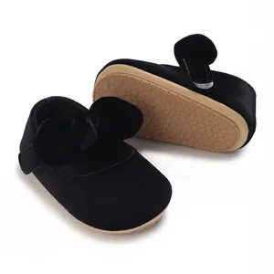 Detailed view of the soft brown sole and plush black velvet fabric of the baby shoes