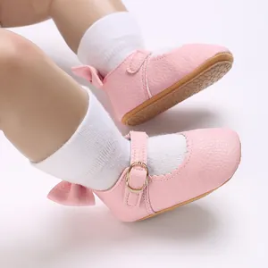 Macro detail of pink leather baby girl shoes featuring a back bow and golden buckle