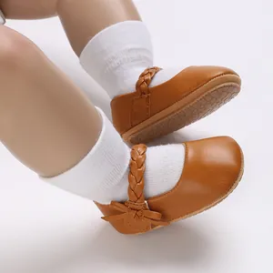 Nahaufnahme von braunen Baby Mädchen Mary Jane Lauflernschuhen mit Flechtriemen.