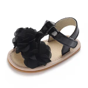 Primer plano de una sandalia para bebé niña con una gran flor de tela negra decorativa