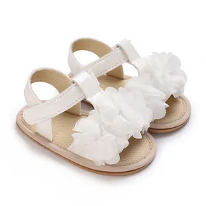 Primer plano detallado de sandalias blancas para bebé con flores de gasa suaves.