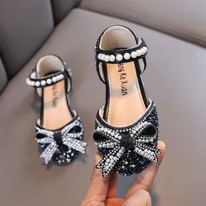 Elegantes zapatos de princesa negros para niña con tira de perlas y lazo brillante.