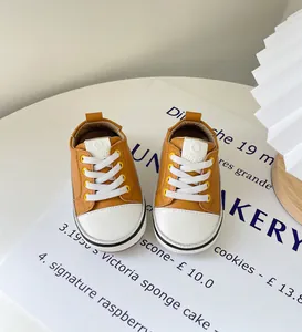 Ingwerbraune Kleinkinder-Sneaker mit weißen Zehenkappen und Schnürsenkeln auf Weiß.
