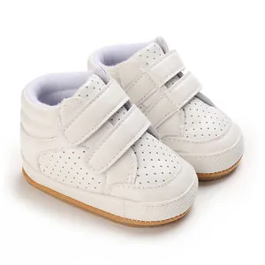 Close-up of white leather baby walking shoes with velcro straps and breathable holes