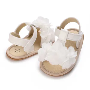 Detalle de sandalias blancas para bebé niña con flores de tela y cierre de velcro.