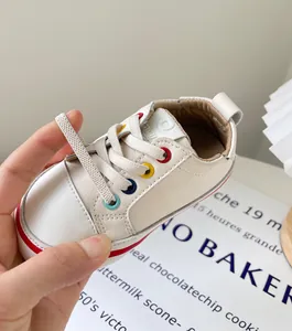 Nahaufnahme von cremefarbenen Kleinkinder-Sneakern mit bunten Ösen und Schnürsenkeln