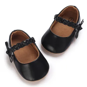 Detailansicht schwarzer Baby-Mary-Janes mit einem geflochtenen Riemen und Schleife.