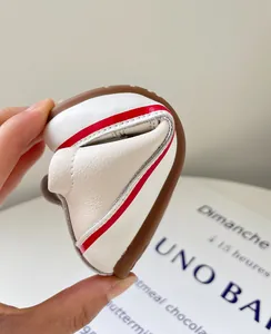 Nahaufnahme der flexiblen weichen Sohle weißer Lauflernschuhe für Kleinkinder mit roten Streifen.