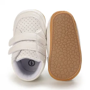 White faux leather baby walker shoes featuring anti-slip rubber soles and velcro straps.