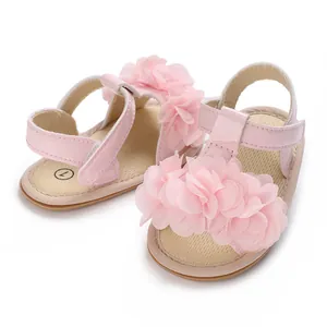 Detalle de sandalias rosas para bebé con flores de tela grandes y suelas suaves antideslizantes.