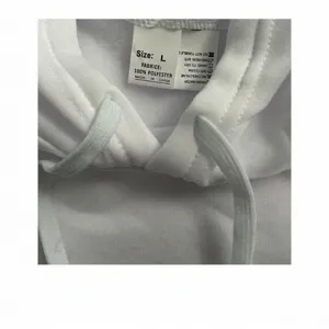 Macro view of white hoodie neck label showing 100% polyester fabric and care instructions.