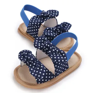 Vista detallada de sandalias de bebé niña con lunares azul marino y bonitos lazos decorativos