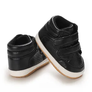 Detailed side view of stylish black faux leather infant sneakers with double velcro straps