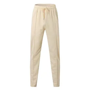Close-up of beige waffle-knit slim joggers with drawstring and pleated front seams