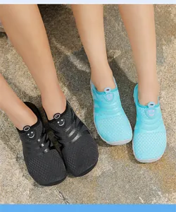 Detalle de zapatos de agua de malla transpirable con logo de cara sonriente en rocas
