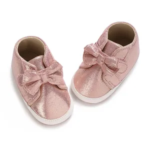 Vue détaillée des chaussures de marche rose brillant avec un grand nœud pour bébé
