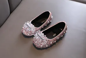 Dettaglio scarpe da principessa rosa per bambine con strass scintillanti e fiocco di perle