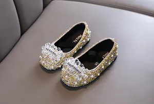 Vista dettagliata delle scarpe da principessa per bambina con strass dorati e perle