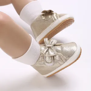 Gros plan de chaussures de marche dorées pour bébé fille avec un nœud délicat