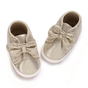 Vue de dessus de chaussures dorées à paillettes pour bébé fille avec nœud et semelle souple