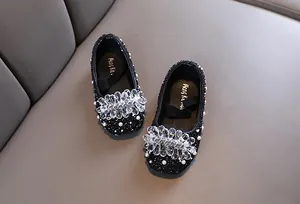 Dettaglio scarpe da principessa nere per bambine con glitter, perle e fiore di cristallo.
