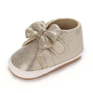Vue détaillée de chaussures pour bébé fille dorées avec un joli nœud scintillant