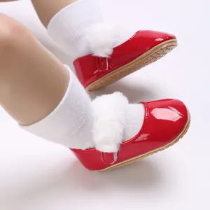 Primo piano di scarpe primi passi in vernice rossa per neonati con bordo in finta pelliccia.