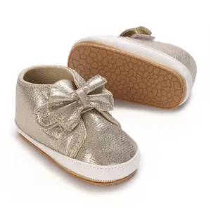 Détail de chaussures bébé dorées pailletées avec nœud et semelles souples