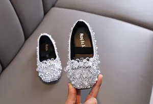 Dettaglio di scarpe da principessa argento per bambina con strass e perle lucide