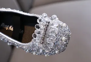 Primo piano dei dettagli scintillanti in strass e perle su scarpe da principessa argento.