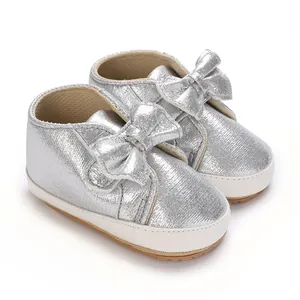 Détail de chaussures argentées pailletées pour bébé avec nœuds et semelles souples