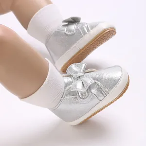 Gros plan de chaussures de marche pailletées argentées avec un nœud pour bébé fille