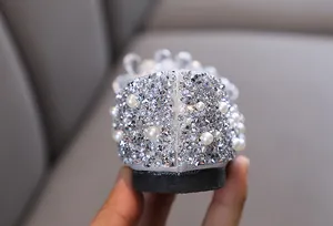 Dettaglio delle decorazioni con strass scintillanti e perle su scarpe argento da bambina