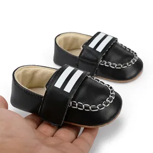 Nahaufnahme von schwarzen Baby-Lauflernschuhen mit weißen Streifen und weicher Sohle