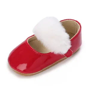 Dettaglio della scarpa da primi passi per neonati in vernice rossa con pompon bianco.