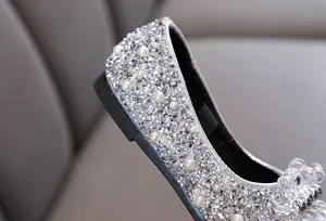 Dettaglio macro di scarpa da principessa argento per bambina con strass e perle