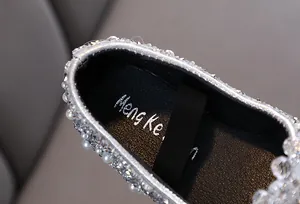 Dettaglio ravvicinato di scarpe da principessa argento per bambina con strass e perle