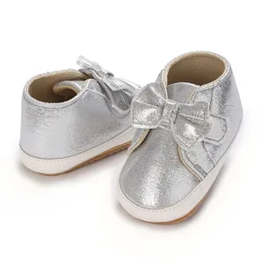 Gros plan de chaussures de marche souples argentées pour bébés filles avec nœud décoratif