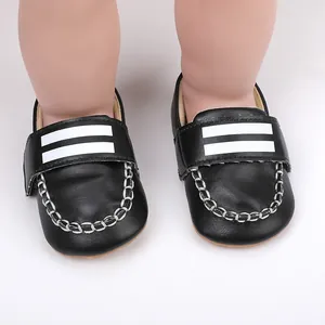 Nahaufnahme von schwarzen Babyschuhen mit weißen Streifen und dekorativen Nähten