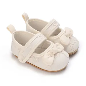 Detalle de zapatos de princesa para bebé en color crema con encaje y un lazo