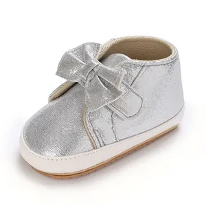Détail d'une chaussure de marche bébé à paillettes argentées avec un gros nœud