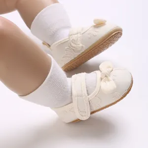 Detalle de zapatos de princesa para bebé en color crema con encaje y lazo