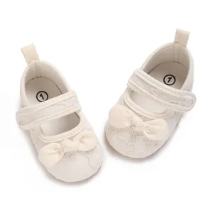 Detalle de zapatos de princesa para bebé blancos con lazo suave y bordado floral
