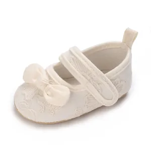 Detalle de zapatos de princesa para bebé crema con lazo y bordado floral