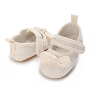 Vista detallada de zapatos de princesa beige para bebé con bordados y un lazo