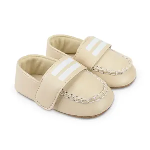 Detailansicht cremefarbener Baby-Lauflernschuhe mit weißen Streifen und Nähten.