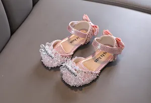 Nahaufnahme rosa Mädchen Prinzessinnenschuhe mit Kristallblume und Schleife.