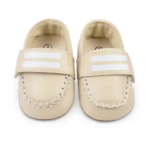 Detailansicht beige Babyschuhe mit weißen Streifen und Klettverschluss.
