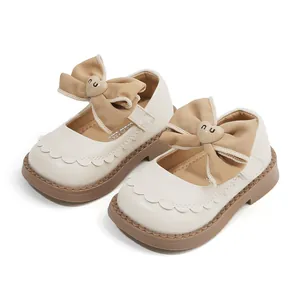 Zapatos Mary Jane crema para niña pequeña con lazo grande caqui y detalle de corazón.