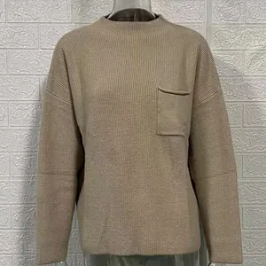 Détail rapproché d'un pull en maille beige avec poche poitrine et texture côtelée.